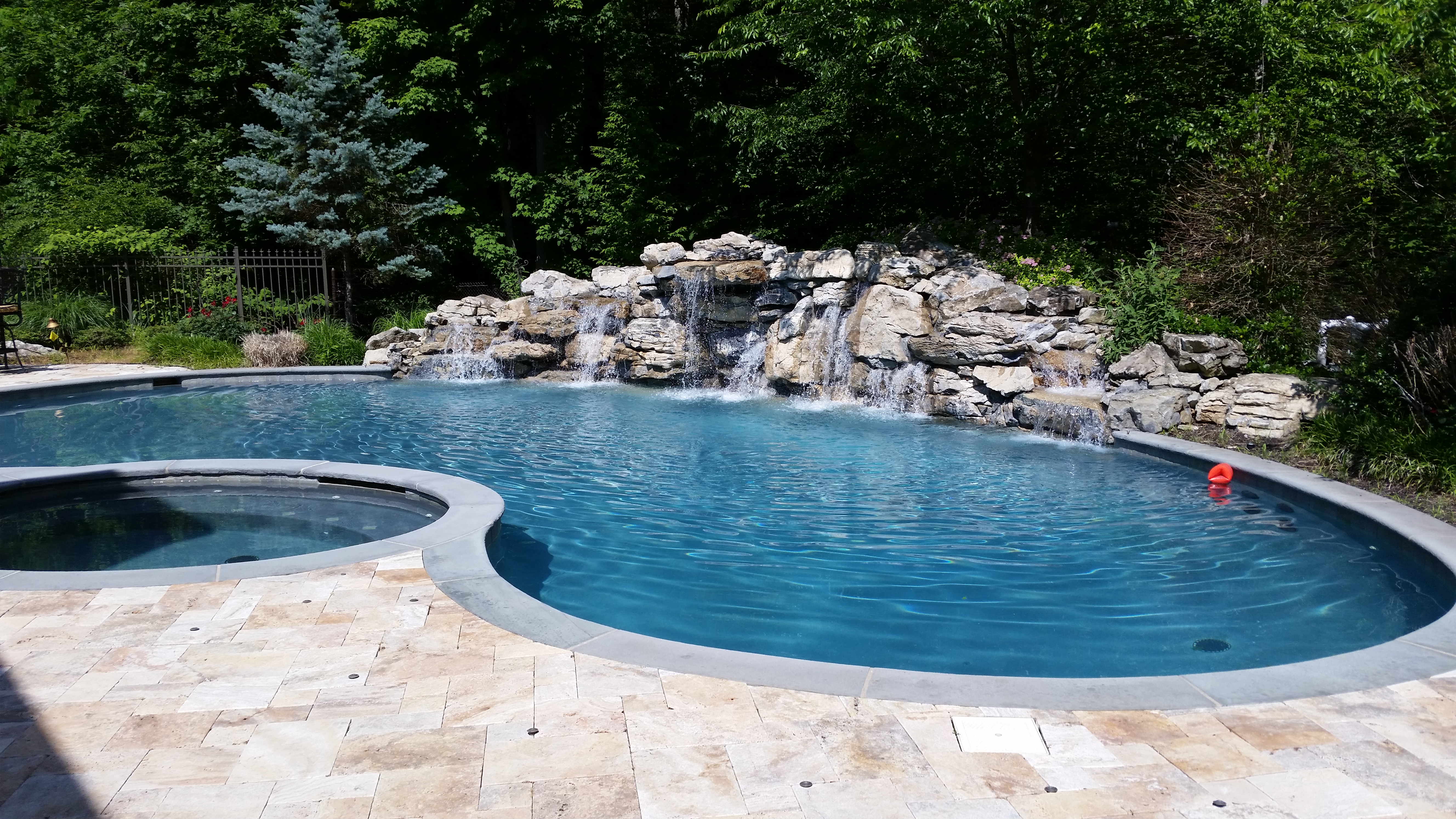 In-ground pool with rock waterfall and stone patio